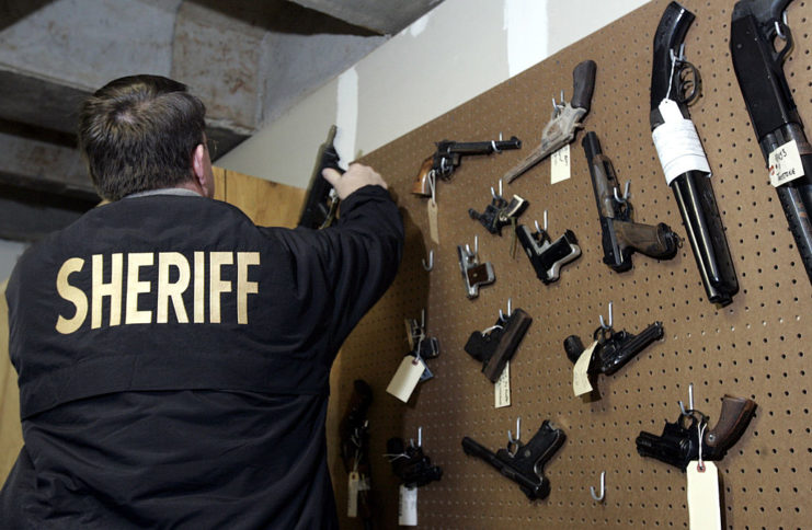 Sheriff standing before a wall of seized guns