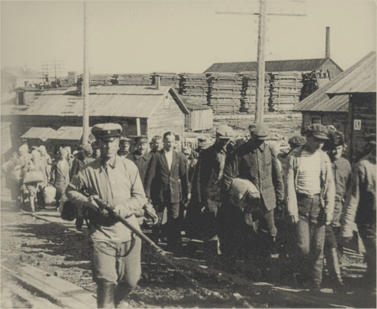 Russian officer walking along a line of male prisoners