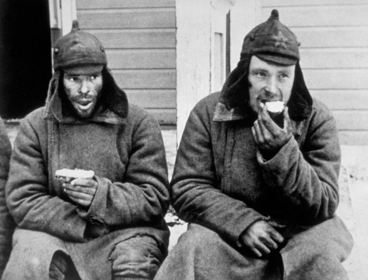 Two Russian prisoners eating their rations in a Finnish POW camp behind the lines.  (Photo Credit: Central Press/Getty Images)