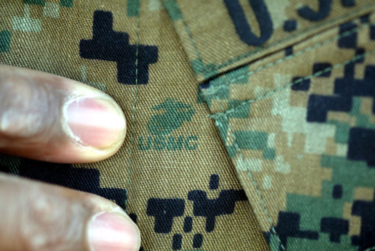 Two fingers pointing toward the US Marine Corps logo on a uniform