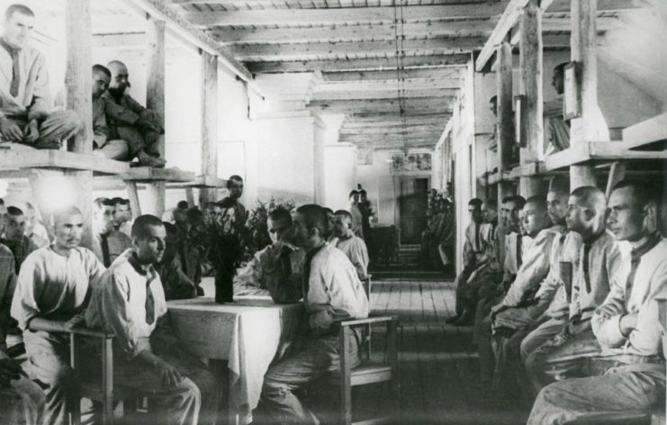 Male prisoners sitting around tables and on bunkbeds