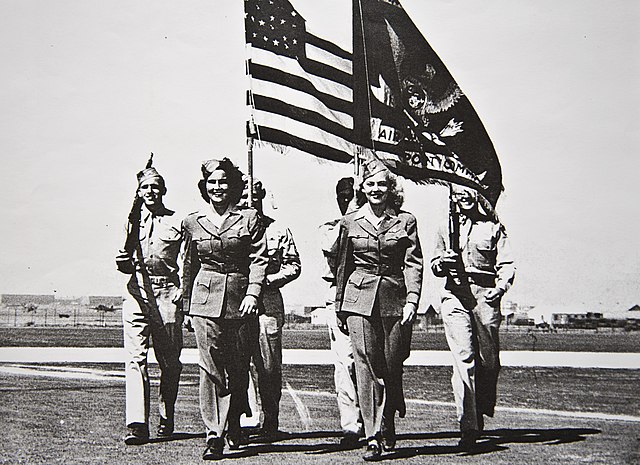Six WASP members carrying flags