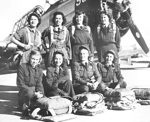 Eight WASP members posing in front of an airplane