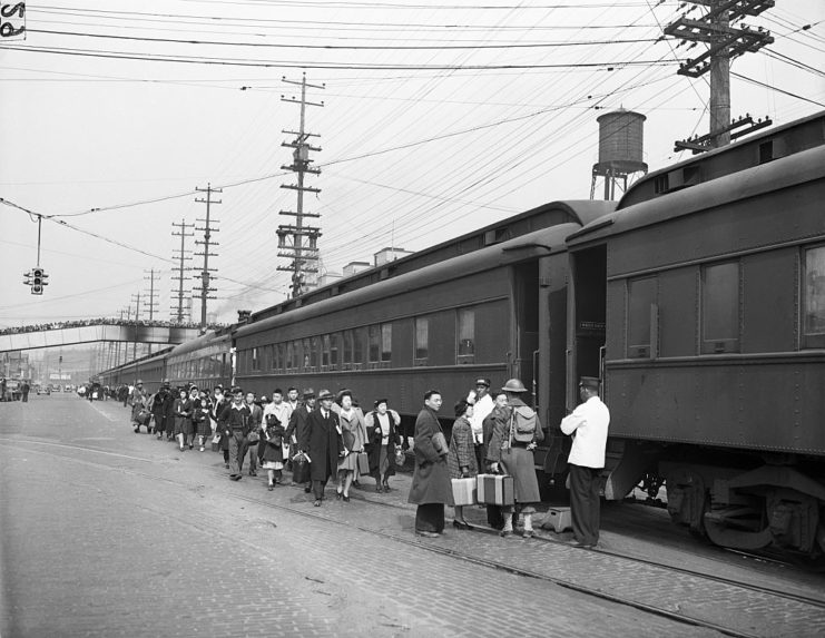 Japanese-Americans lining up along the outside of a train