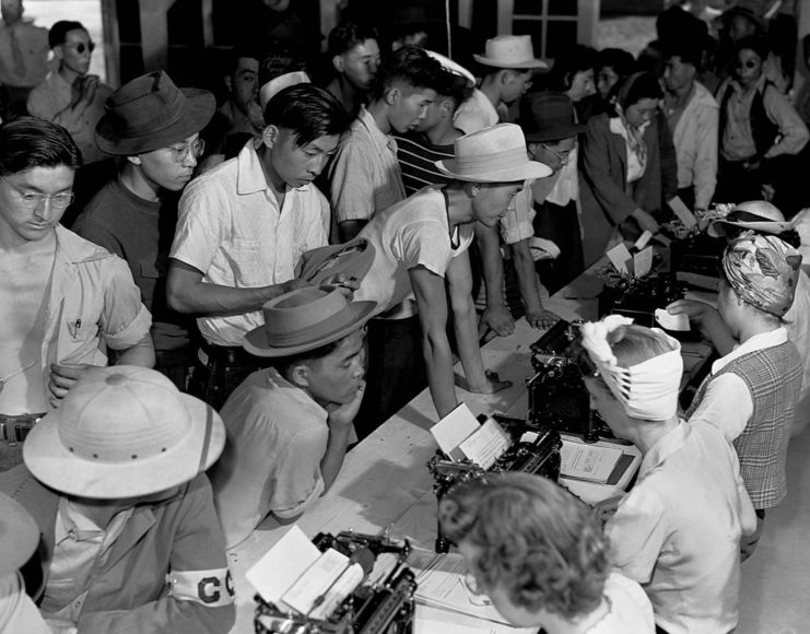 Japanese-Americans standing before a table covered in paperwork