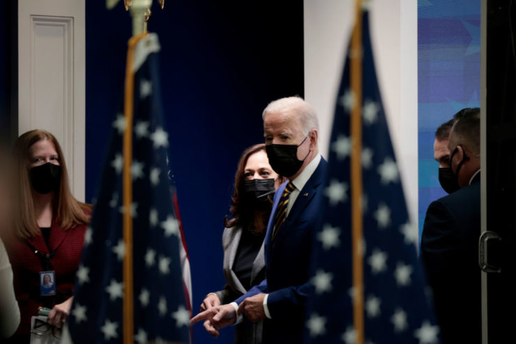 Joe Biden and Kamala Harris walking between two US flags