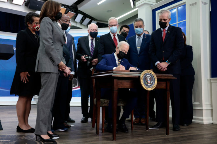 Government officials gathered around Joe Biden at a desk