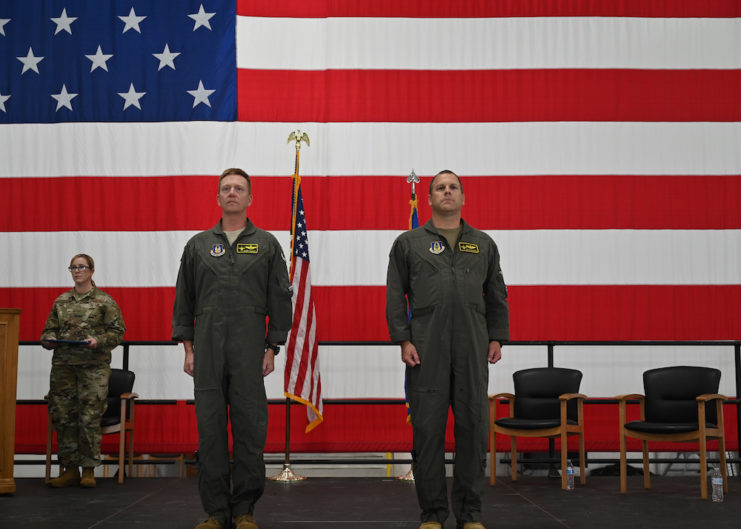 Major Mike "Vago" Hilkert and US Air Force personnel standing in front of the American flag