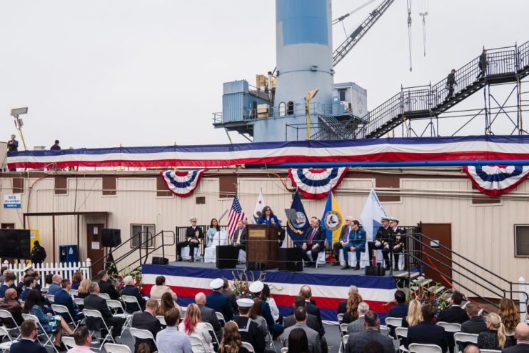 Paul Neira speaking on stage while others watch