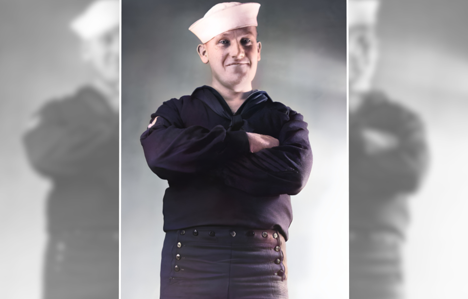 Portrait of a US Navy sailor standing with his arms crossed and wearing 13-button pants