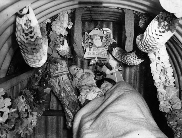 Child sleeping in an air raid shelter decorated for Christmas