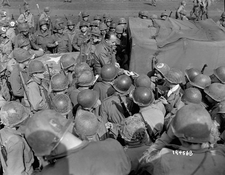 Bing Crosby sitting among a group of US soldiers