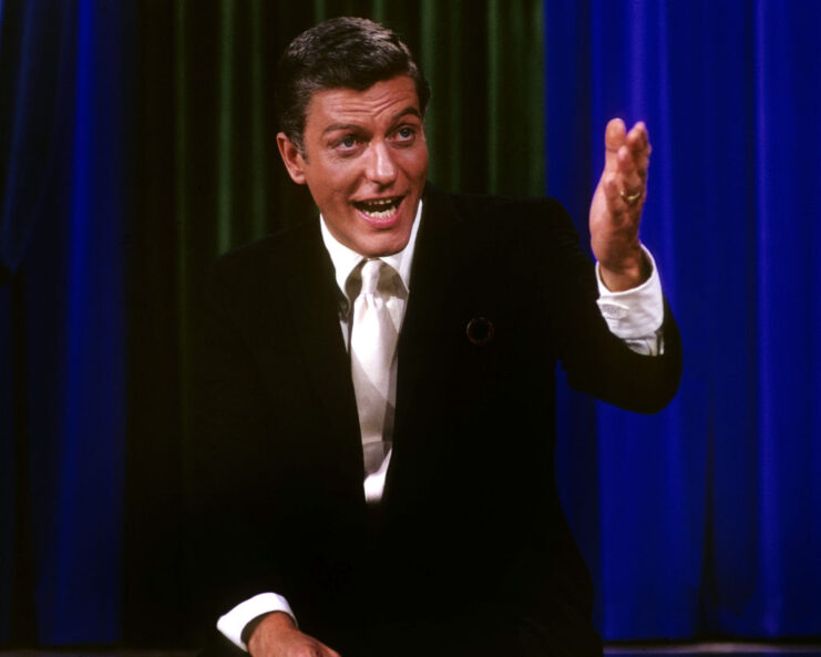 Dick Van Dyke sitting with his hand outstretched