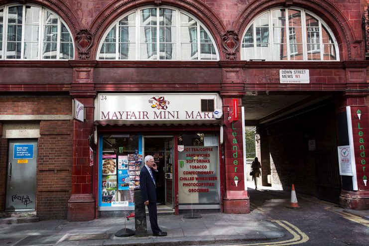 Businessman talking on his cellphone in front of the Mayfair Mini Mart