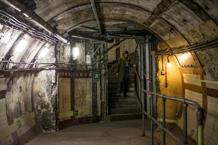 Woman standing in the doorway to a dimly-lit tunnel