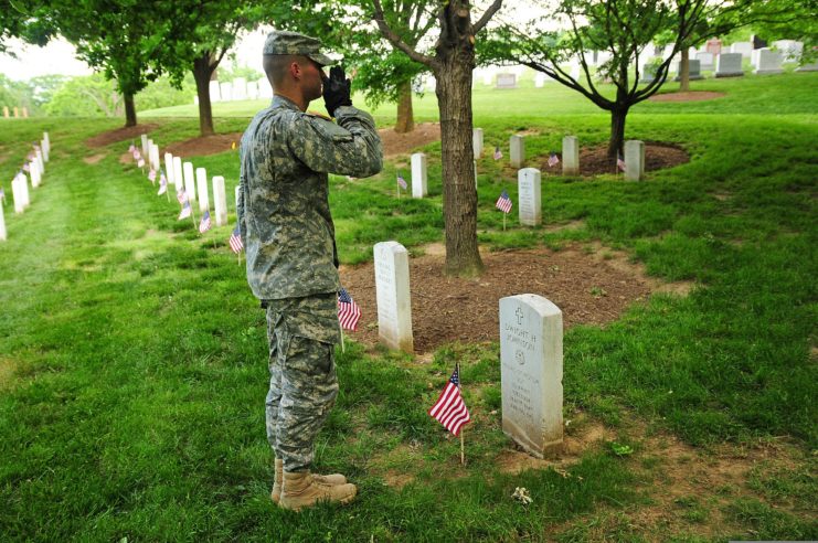 US Army soldier standing at attention in front of Dwight H. Johnson's grave