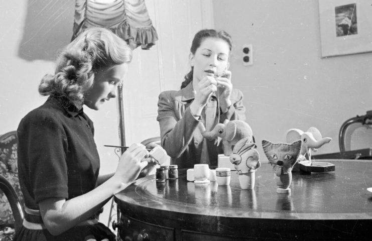 Two women making egg cosies at the dining room table