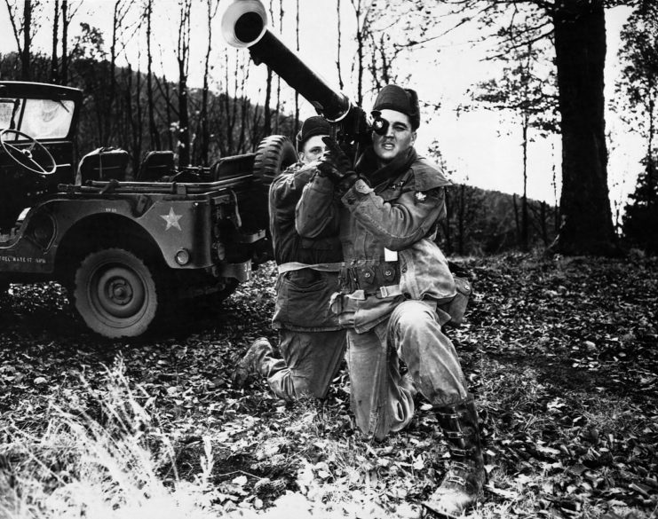 Elvis Presley and another soldier aiming an artillery gun