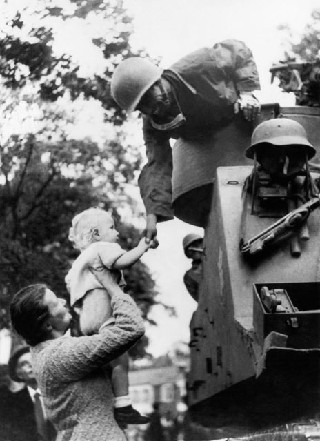 Woman holding up her baby to a French soldier