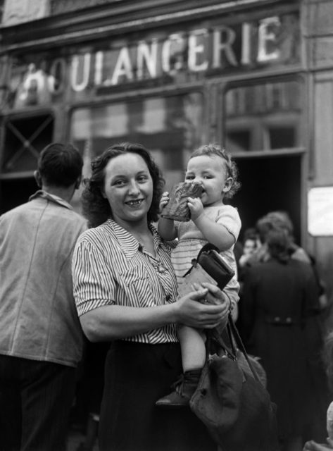 Mother holding her baby, who is eating a slice of bread