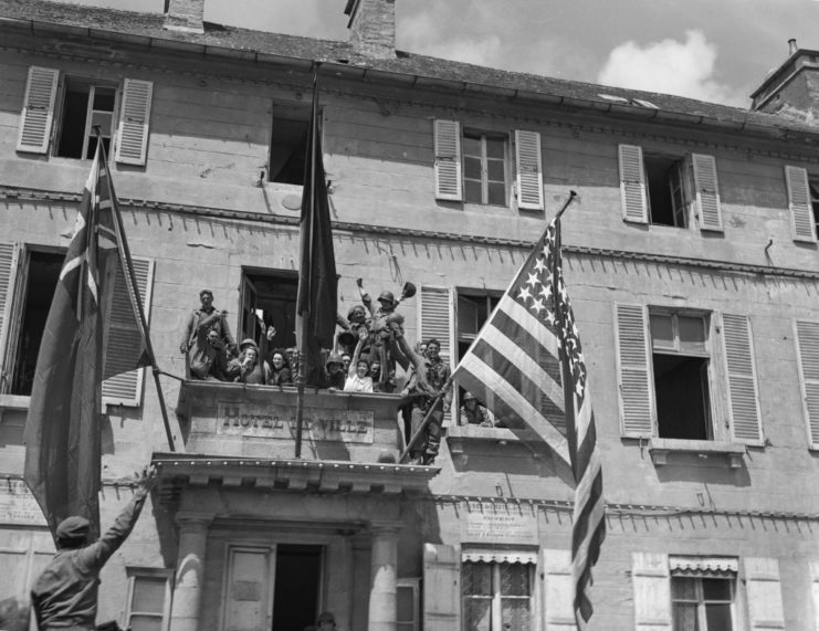 French citizens standing atop a balcony clad with flags