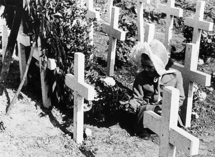 Little girl crouched before a grave