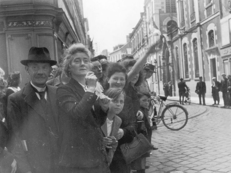 French citizens crowded along the side of a street