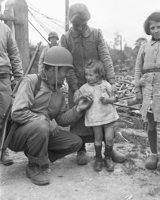 US soldier crouched down before a little girl