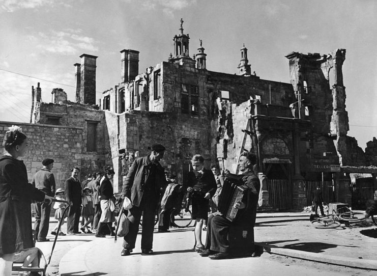 People gathered around a busker playing an accordian