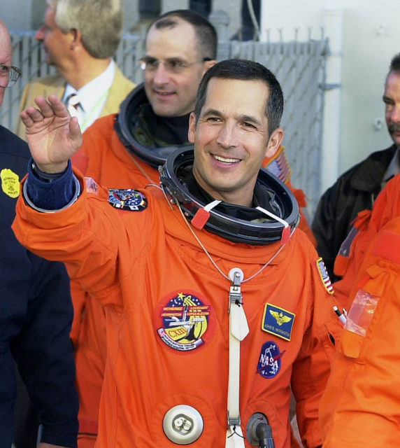 John Herrington waving while wearing a spacesuit