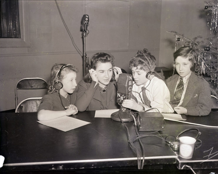 Children gathered around a table with a microphone atop it