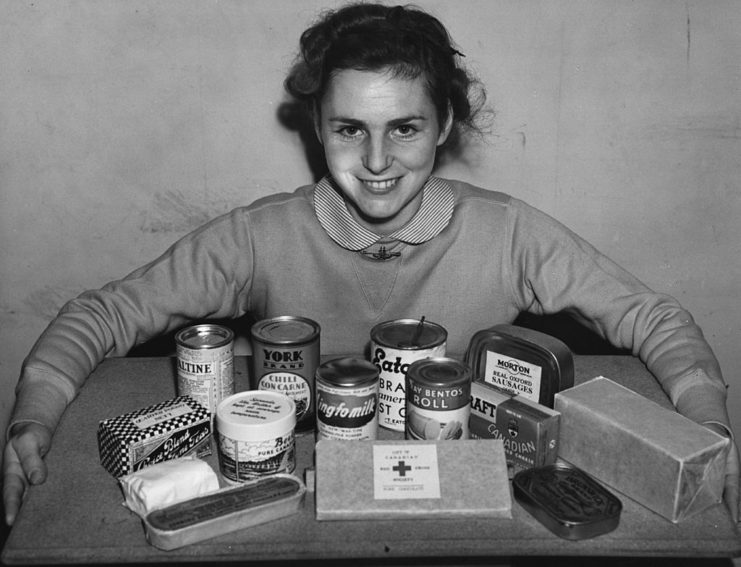 Female Red Cross volunteer displaying canned and boxed rations