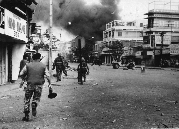 Vietnamese soldiers running toward a smoke-shrouded building