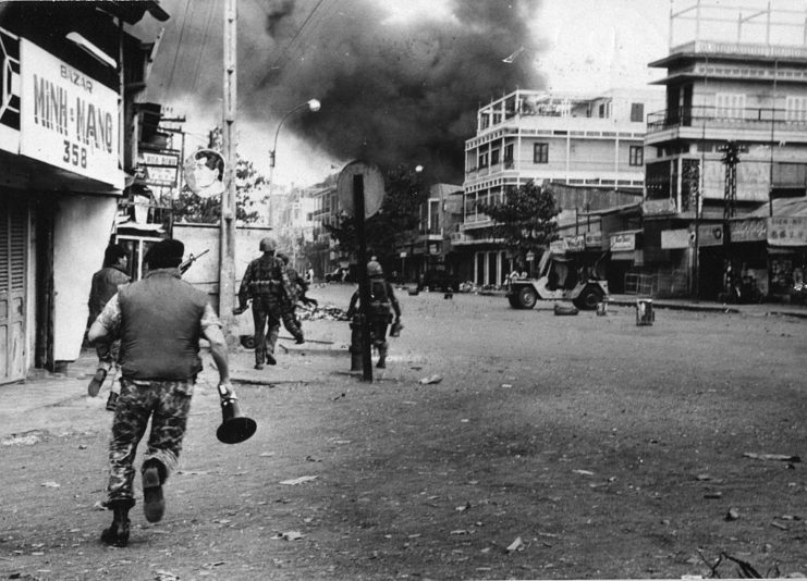 Vietnamese soldiers running toward a smoke-shrouded building
