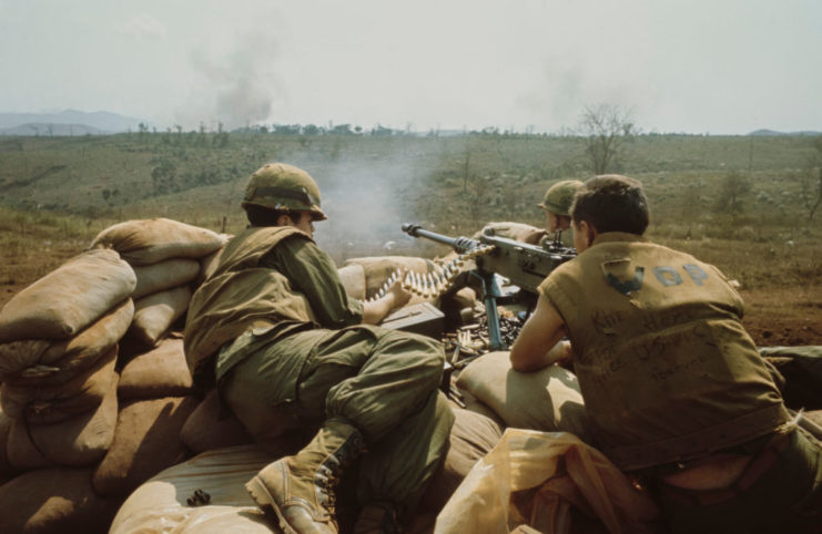 Two US Marines crouched over an M2 Browning machine gun