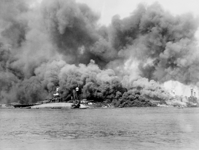 Smoke rising above a capsized USS Oklahoma (BB-37)