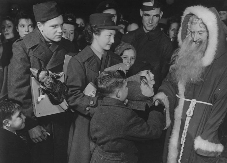 Santa Claus shaking the hand of a little boy while others watch