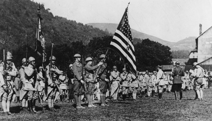 US soldiers standing together, with one holding the American flag
