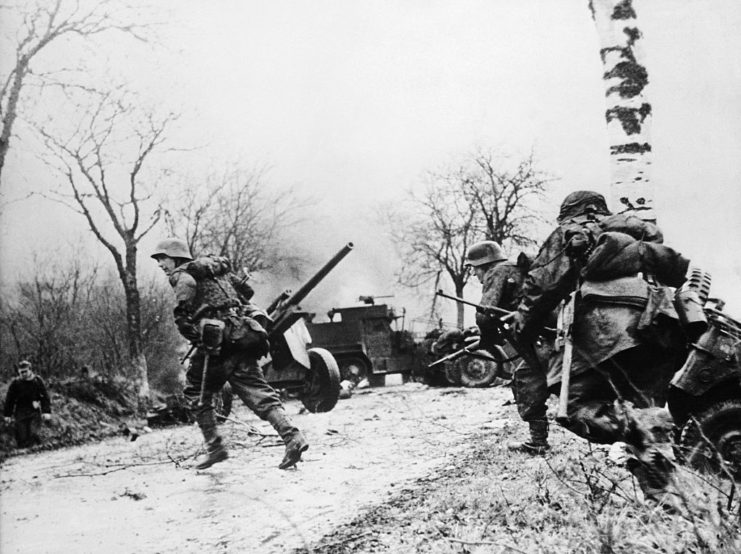 German soldiers running across a snow-covered road