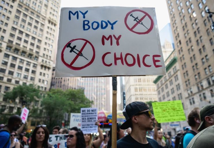 Protestors holding up anti-COVID-19 vaccine and mandates signs