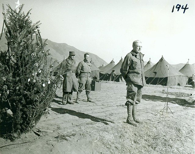 Homer Litzenberg standing in front of a Christmas tree