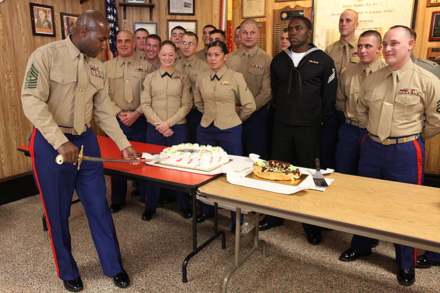 Marines watching Sergeant Major Allen L. Tanner cutting a cake with a mameluke sword