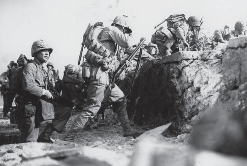 7TH MARINES assault troops cross the sea wall on BLUE Beach 2, seconds after landing on Okinawa. (Photo Credit: USMC / ww2db.com/ public domain)