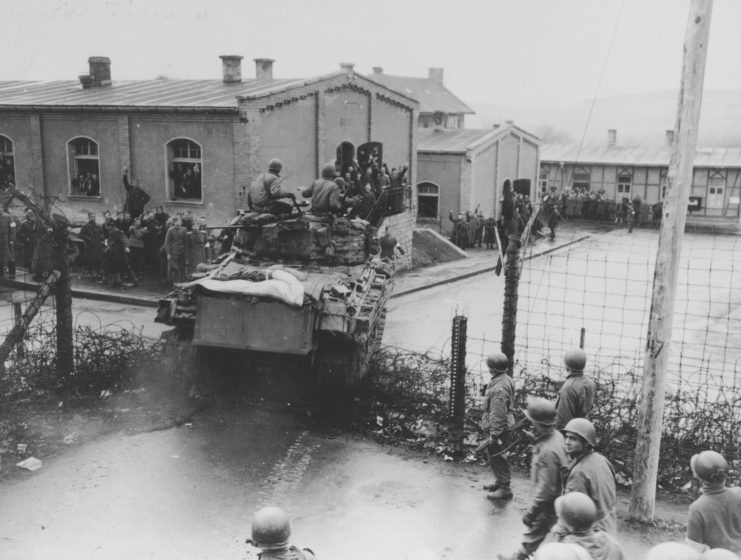 Tank crashing through the barbed wire fence surrounding a German prison camp