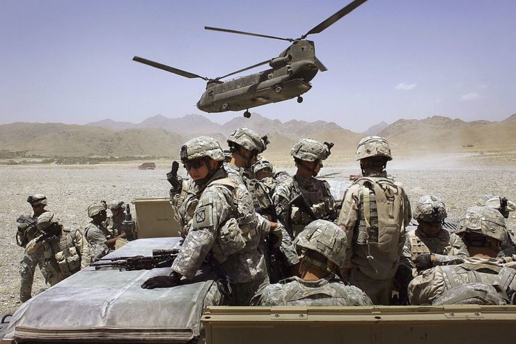 US troops from the 10th Mountain Division standing below a military helicopter