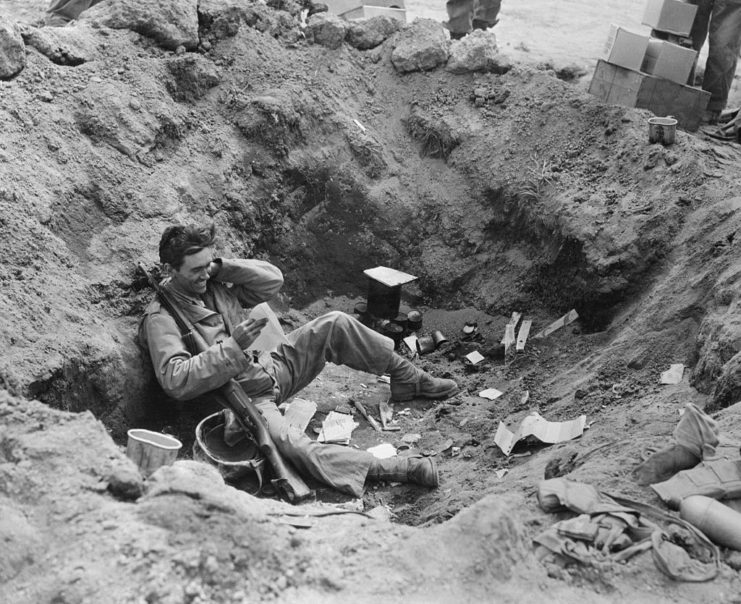 US Marine reading his mail while sitting in a foxhole