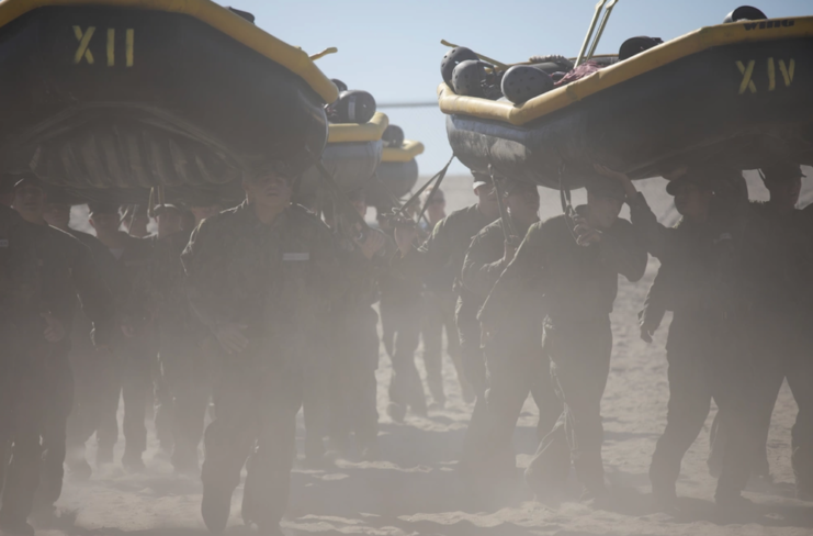 Navy SEAL trainees carrying rafts over their heads