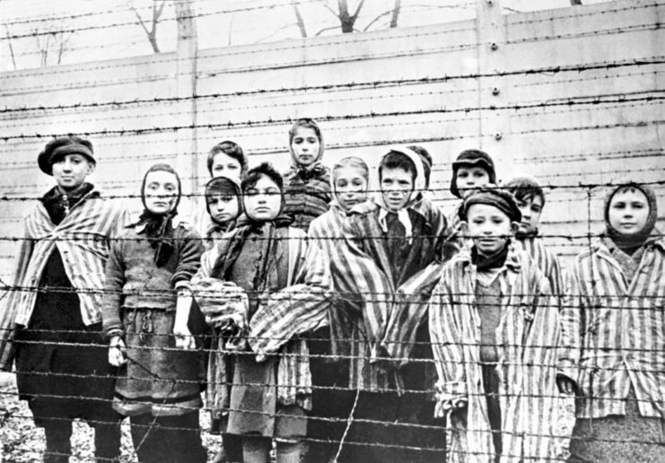 Children standing behind barbed wire at Auschwitz