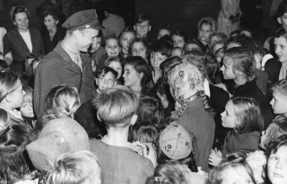 Gail Halvorsen standing among a crowd of children