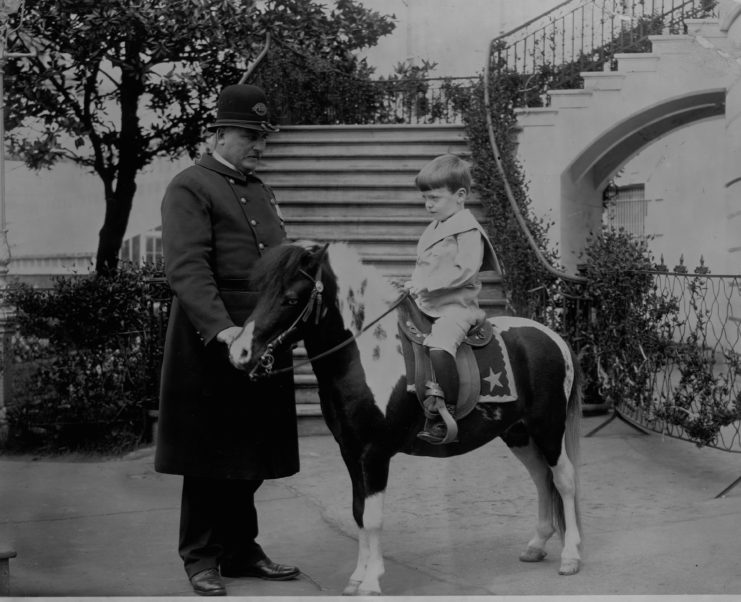 Theodore Roosevelt helps his youngest son, Quentin, ride on a pony on the White House grounds. 
